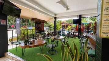 An indoor dining area with tables and chairs, a bar counter, and a green artificial turf floor.