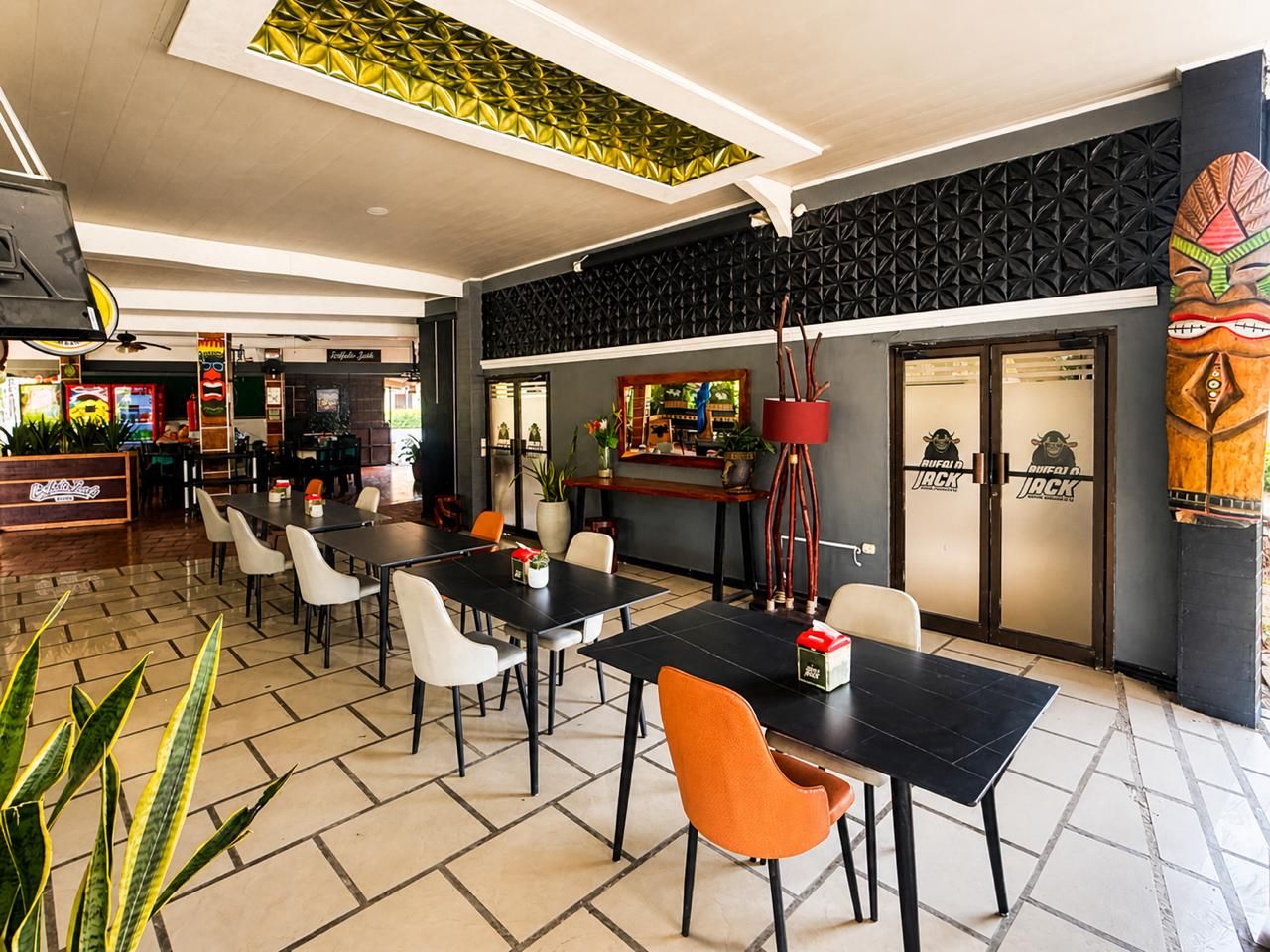 Un restaurante con mesas, sillas, una barra y una pared decorativa.