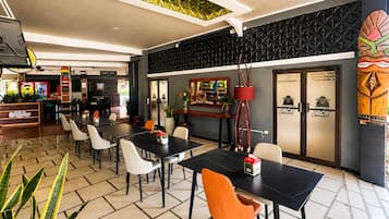Un restaurante con mesas, sillas, una barra y una pared decorativa.