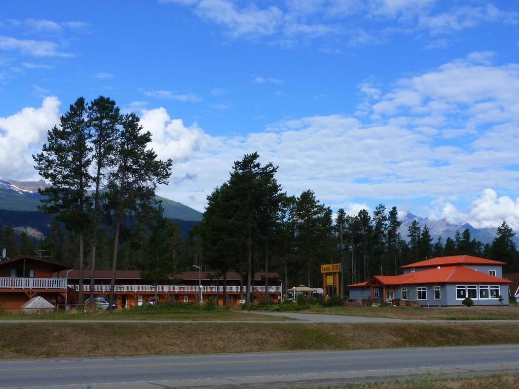 A motel with a red-roofed building, a signboard, and a mountain backdrop.