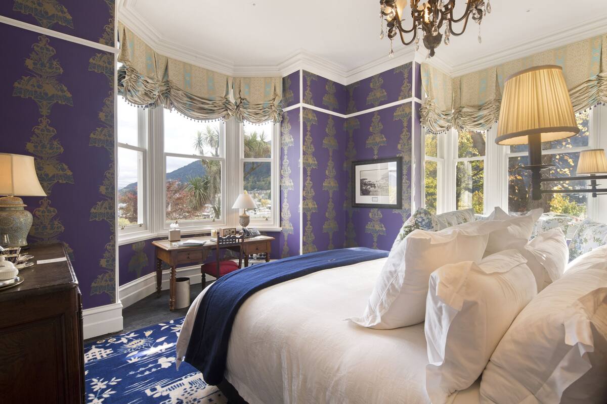Un dormitorio con una cama grande, un escritorio y vistas al exterior.