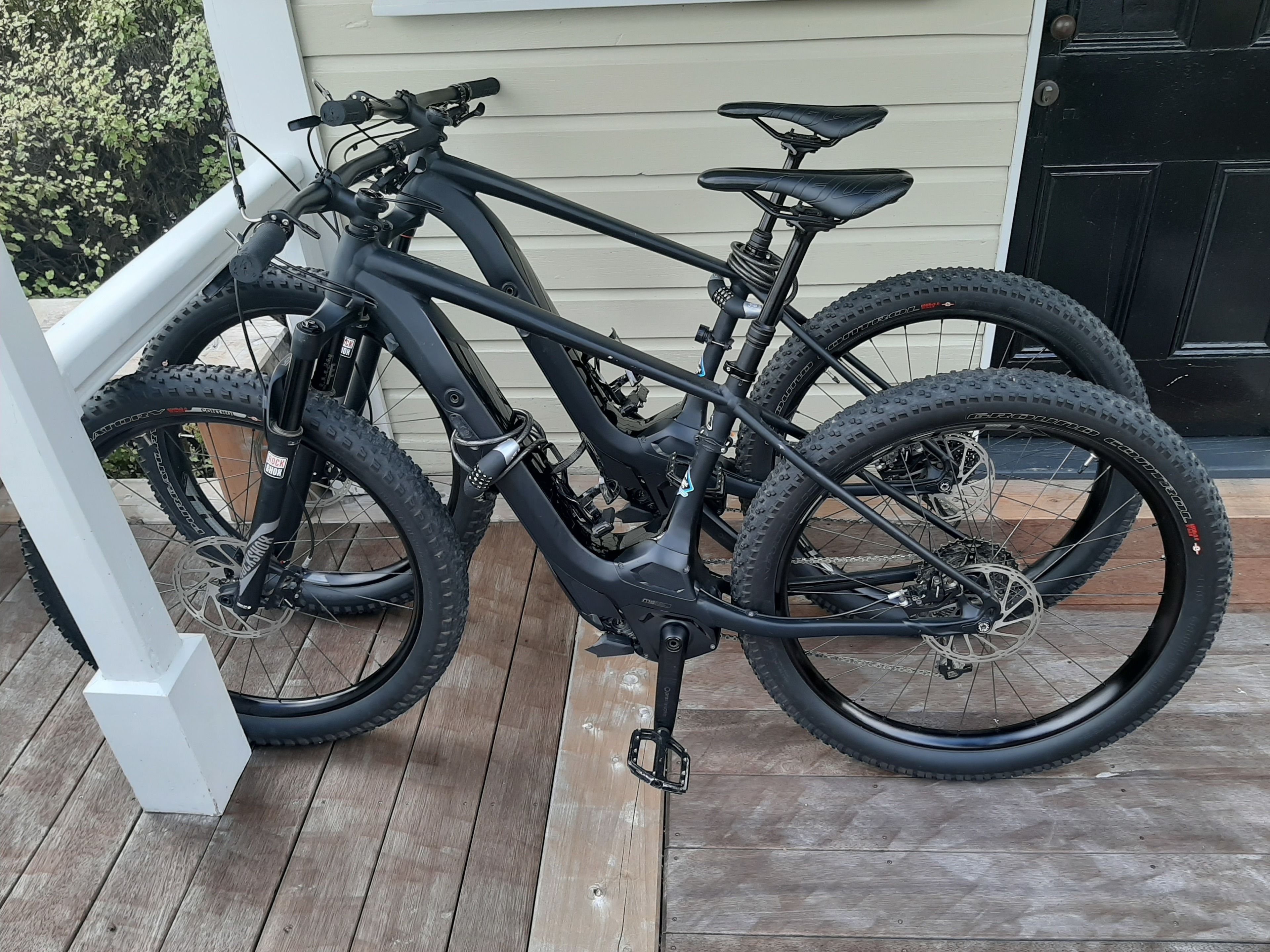 A mountain bike parked on a wooden deck in front of a house.