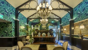 A restaurant with a high ceiling, a chandelier, and tropical wallpaper. - Hulbert House (Queenstown)