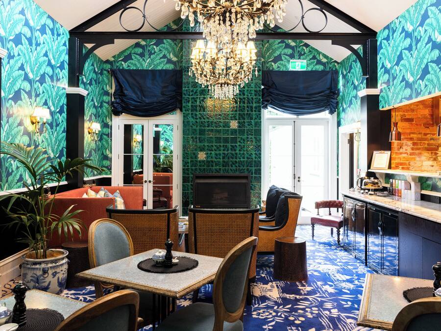 Quarto com área de jantar, bar e parede verde revestida com azulejos, com uma televisão.