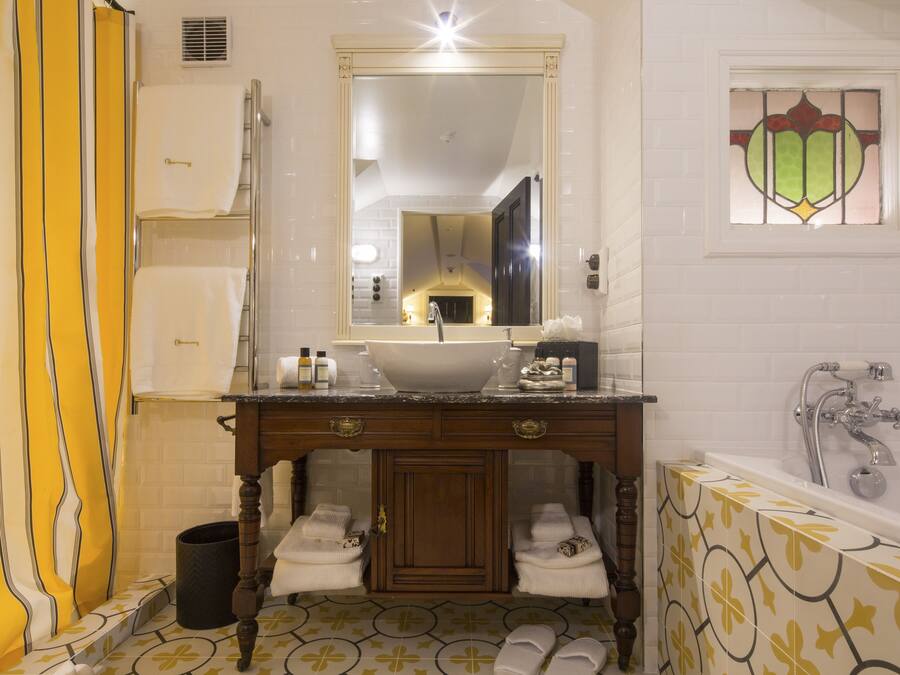 A bathroom with a sink, mirror, and bathtub. There are towels and toiletries on the counter.