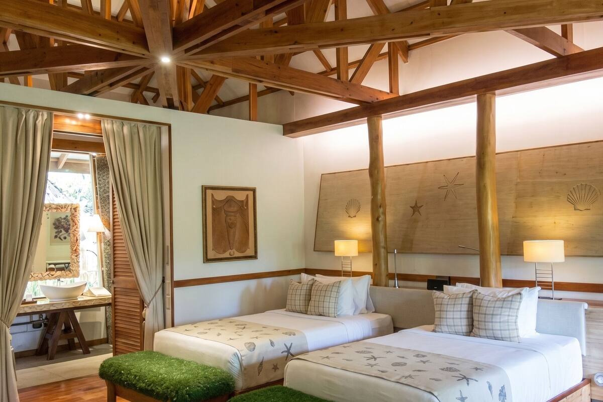 A room with two beds, a wooden ceiling, and a large wall mural.