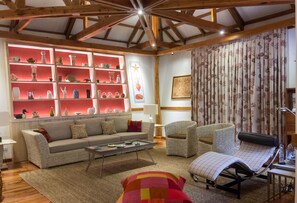 Una sala de estar acogedora con un sofá, sillones, una mesa de centro y una estantería llena de objetos decorativos.