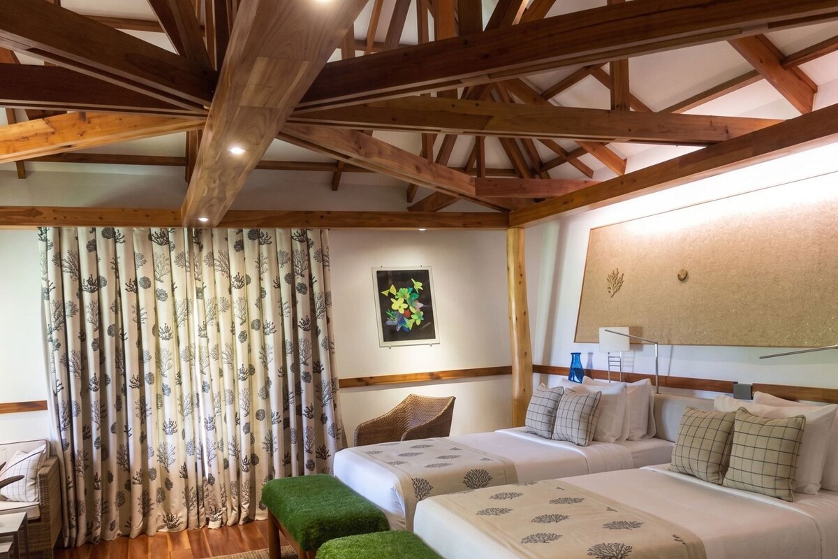 A room with two beds, a desk, and a window with curtains.