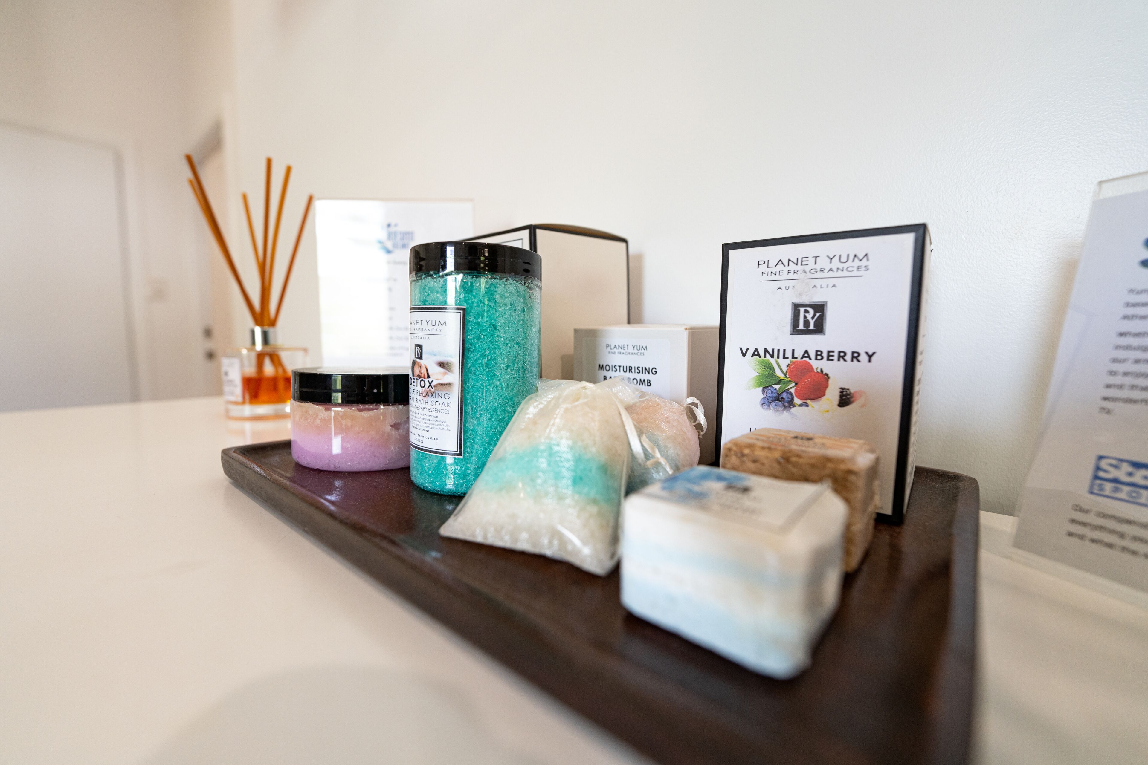 Un plateau contenant divers articles de toilette, notamment un flacon de lotion, un savon et une bougie parfumée.