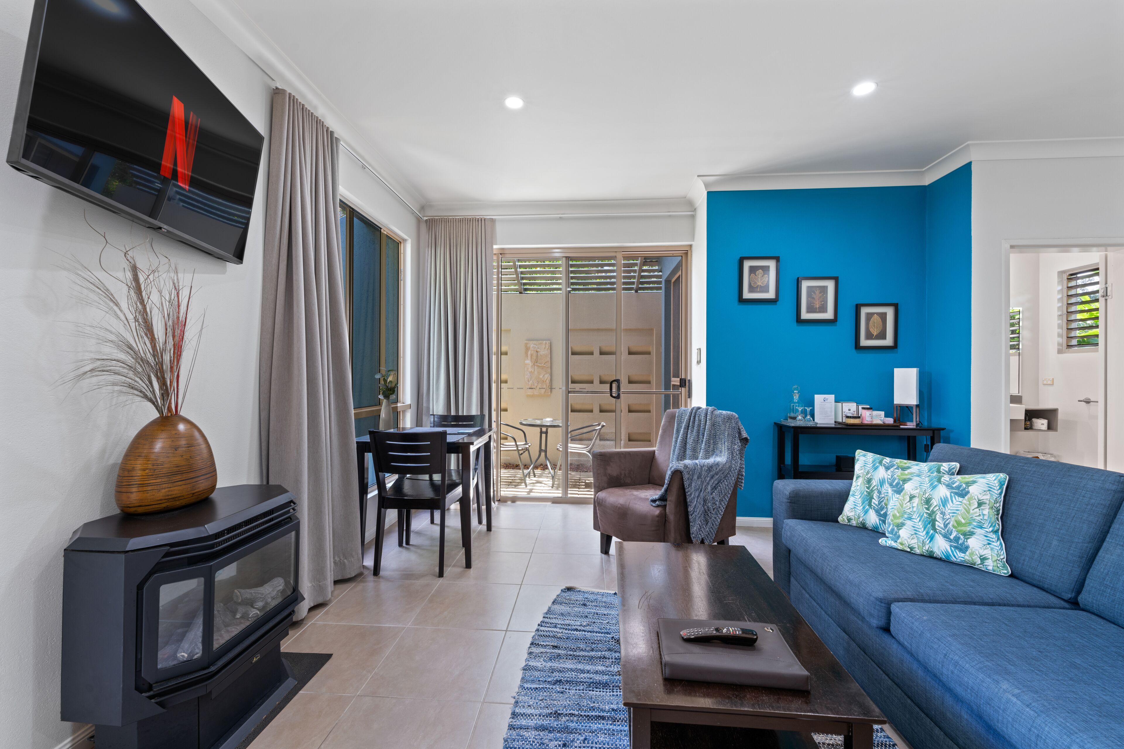 Ein modernes Wohnzimmer mit Kamin, einem blauen Sofa und einem Essbereich mit Tisch und Stühlen.