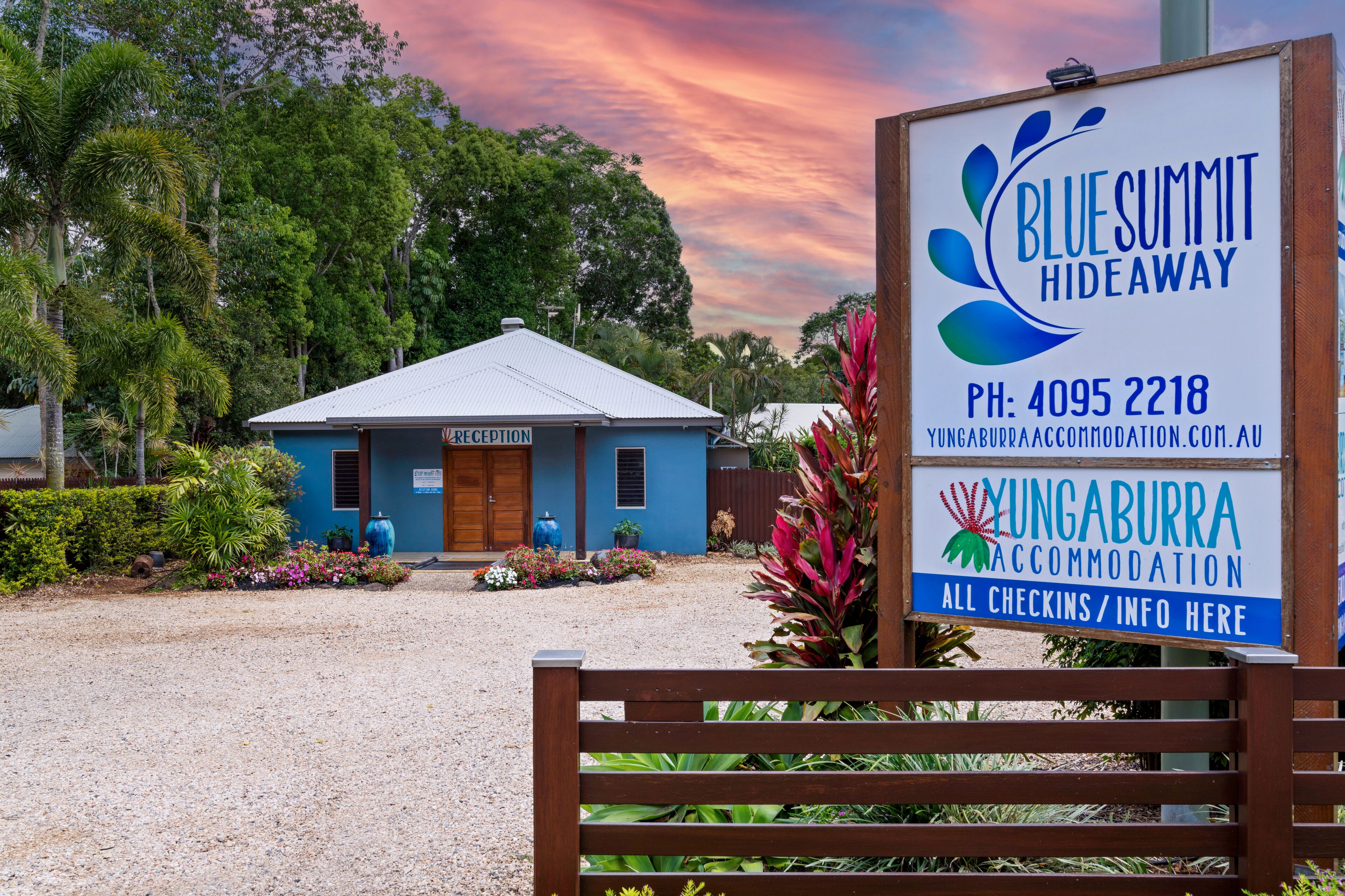 A reception area with a sign for Blue Summit Hideaway, a reception desk, and a small building with a blue roof.
