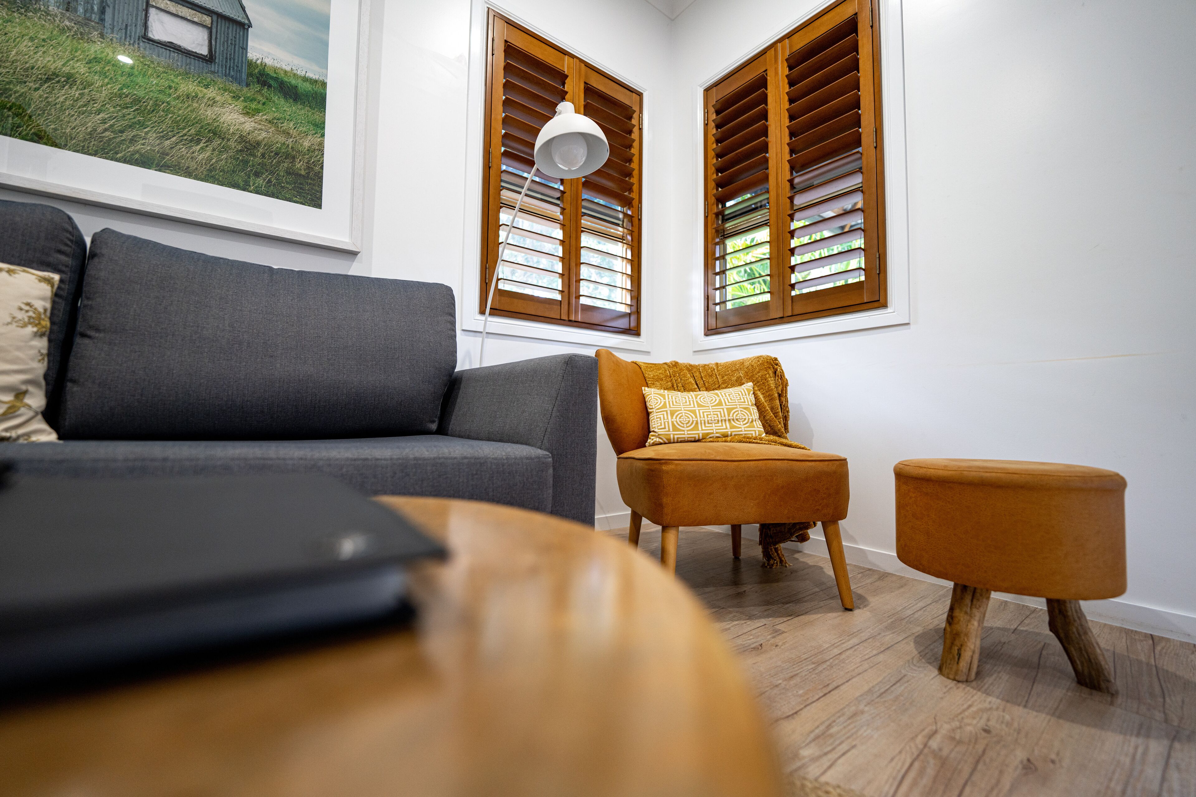 Ein modernes Wohnzimmer mit einem grauen Sofa, einem Holztisch und einem kleinen orangefarbenen Sessel.