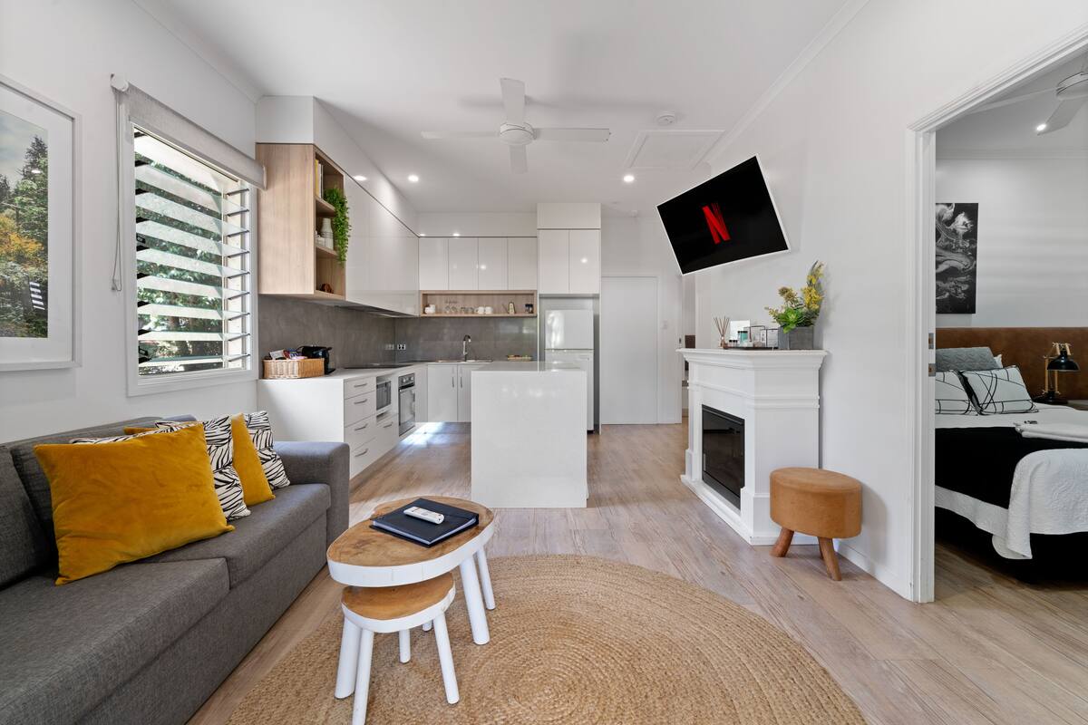 Un área de sala y comedor moderna y de concepto abierto con un sofá, una mesa de centro y un televisor montado en la pared.