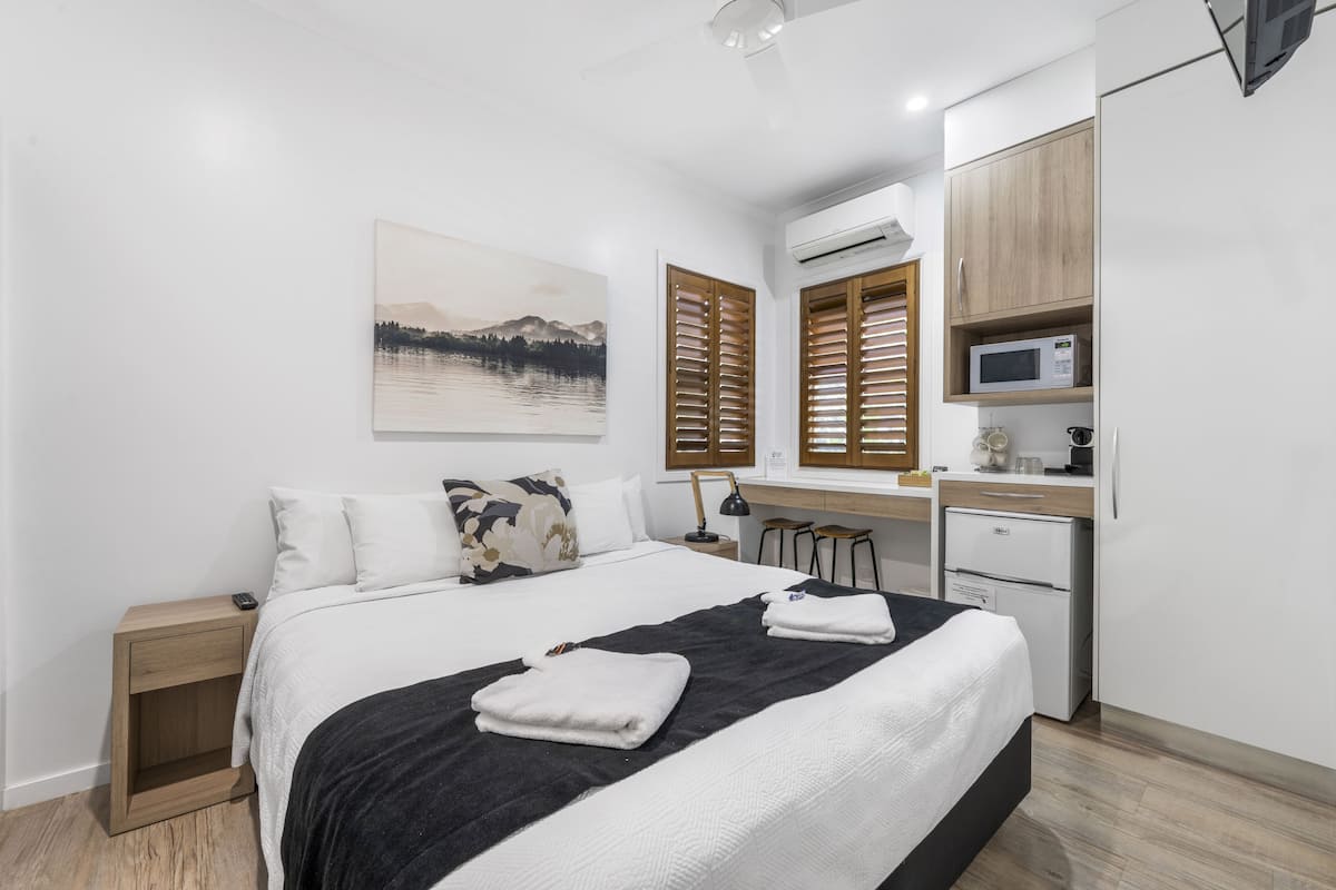Un dormitorio moderno con cama, mesitas de noche, un escritorio y un microondas.