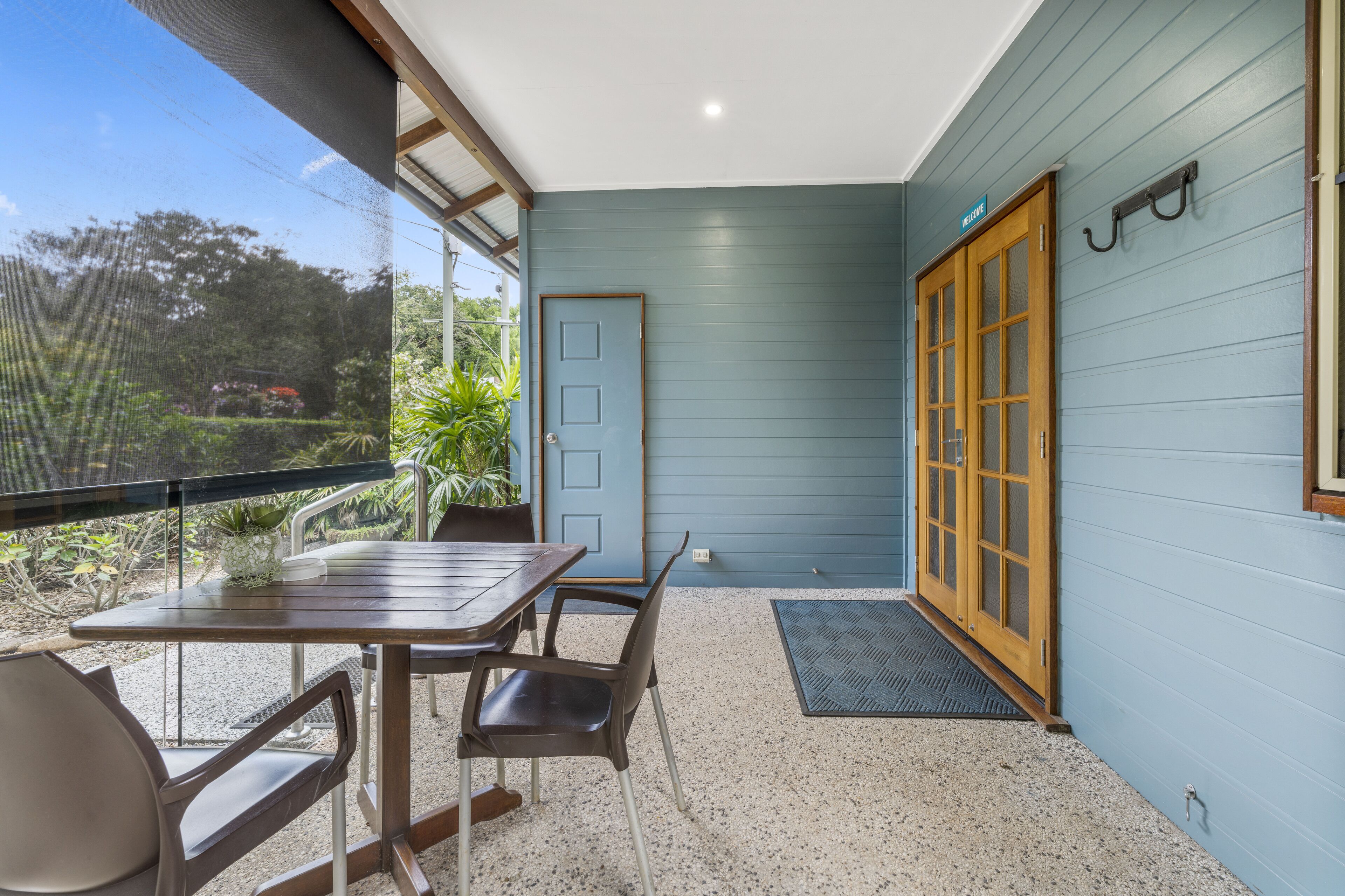 A room with a table and chairs, a door, and a view of the outdoors.