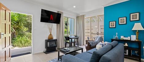 A modern living room with a blue sofa, a flat-screen TV, and a fireplace.