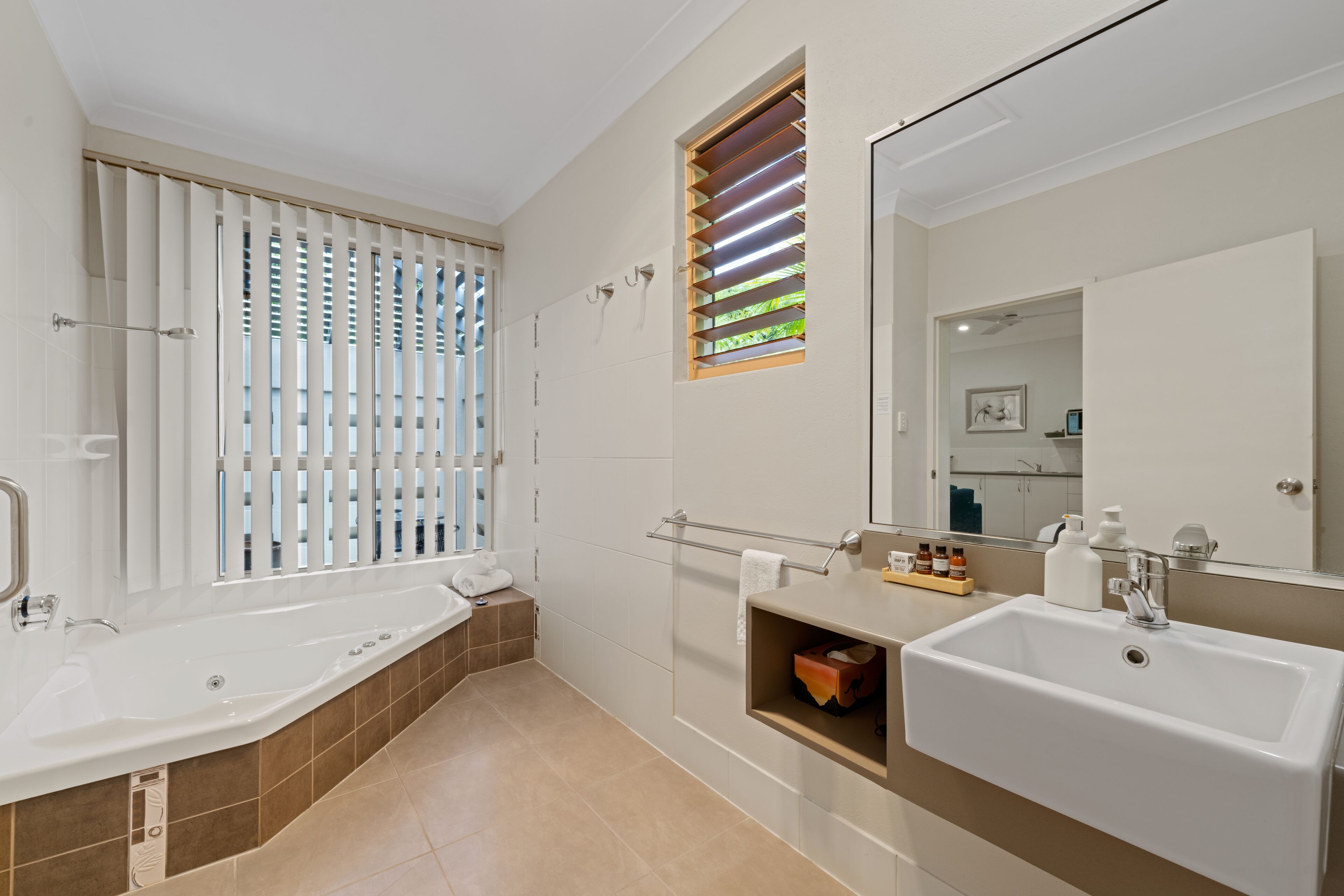 A modern bathroom with a bathtub, a sink, and a large mirror.
