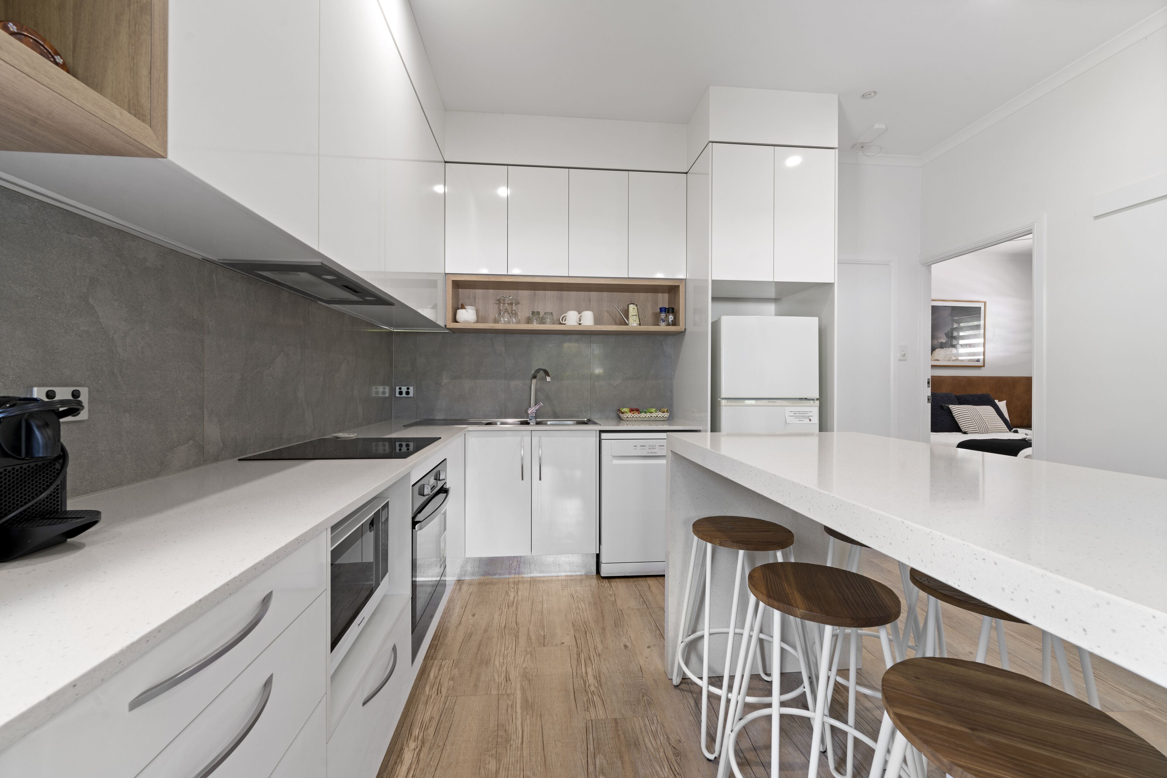 Una cocina moderna con armarios blancos, encimera de madera, horno empotrado y cafetera.