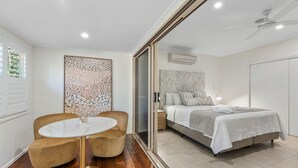 A modern bedroom with a bed, bedside tables, and a round table with chairs. - Blue Summit Hideaway (Yungaburra)