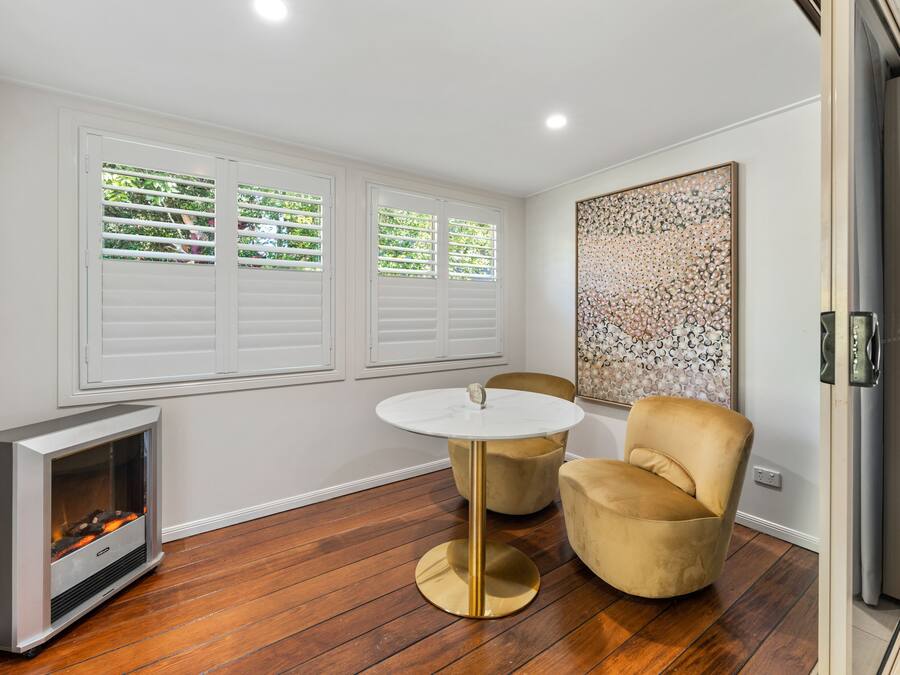 A modern room with a fireplace, two chairs, a round table, and a large abstract painting on the wall.