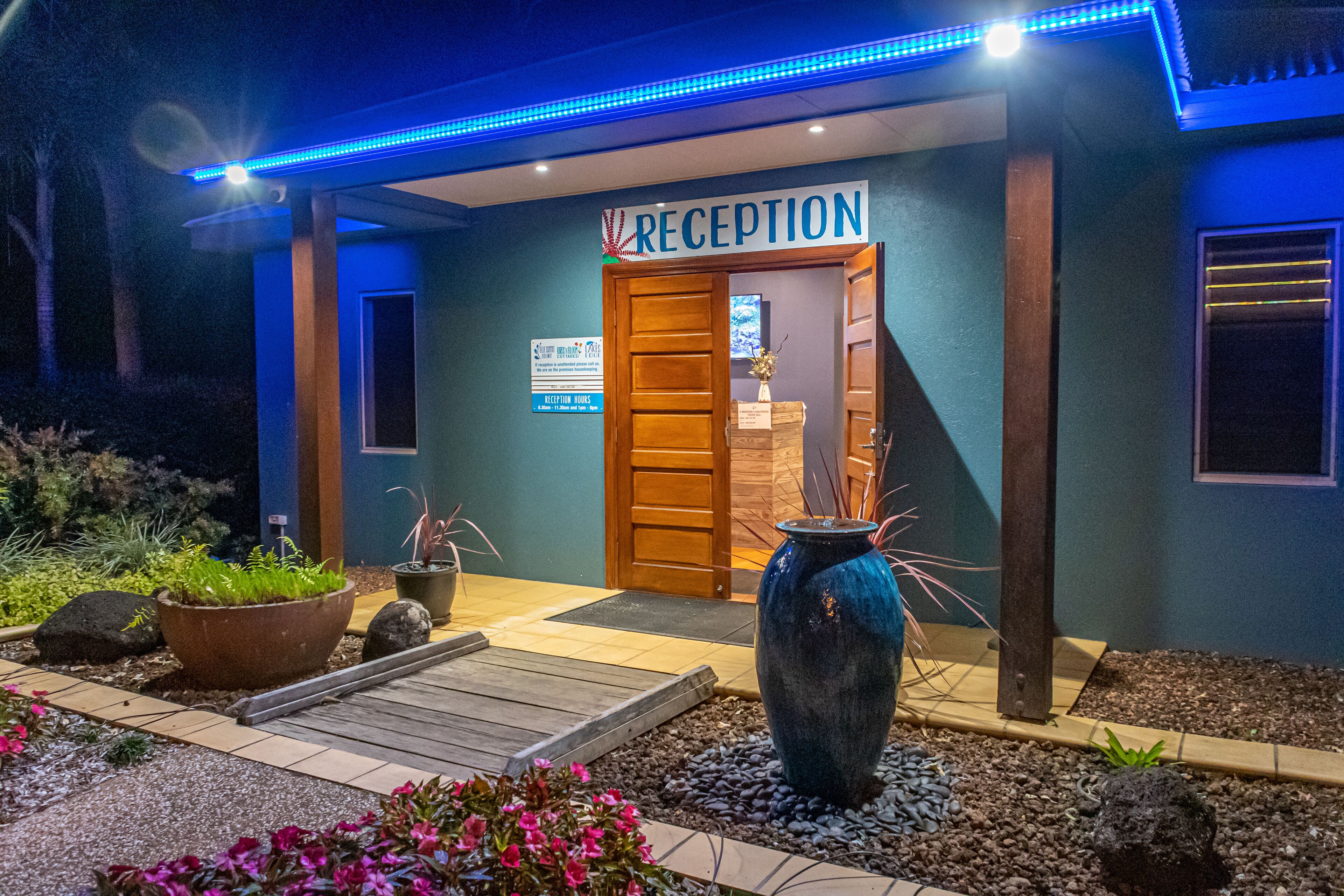 A reception area with a sign, a wooden door, and a blue-lit entrance.