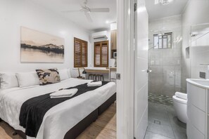 Ein modernes Hotelzimmer mit einem großen Bett, einer Duschkabine und Blick ins Freie.