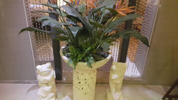 Una planta en maceta con una maceta decorativa y dos esculturas con forma de animales blancos sobre una mesa.