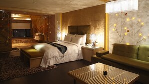 A modern hotel room with a large bed, a green sofa, a wooden coffee table, and a decorative wall with lights. - Dryad Motel (Tainan)