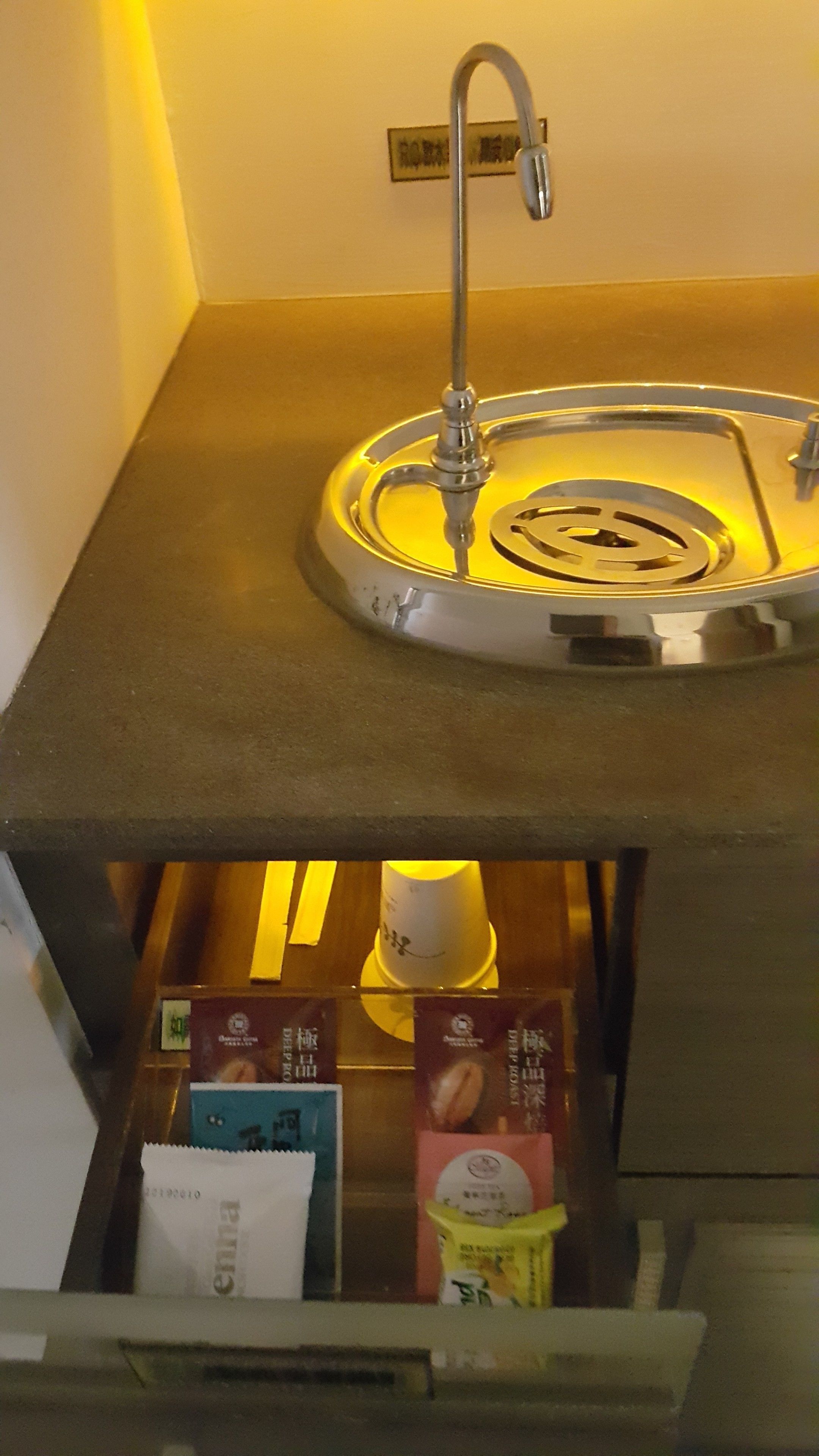 Uma pia com torneira e um porta-copos embaixo. Há itens de comida embalados à vista.