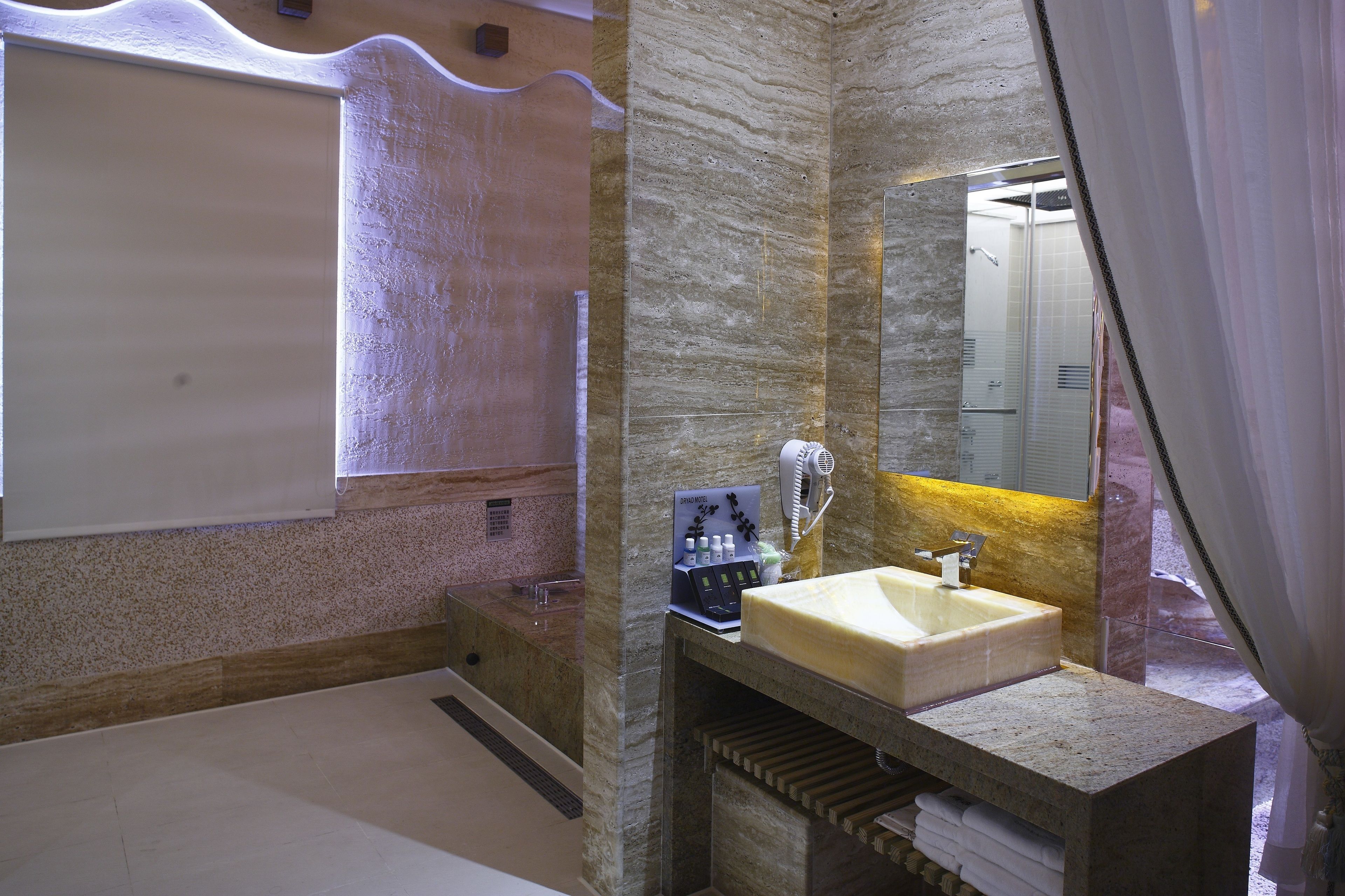 A modern bathroom with a marble sink, a large mirror, and a bathtub.