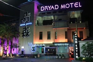 The exterior of the Dryad Motel with illuminated signage, a brick facade, and a gated entrance. - Dryad Motel (Tainan)