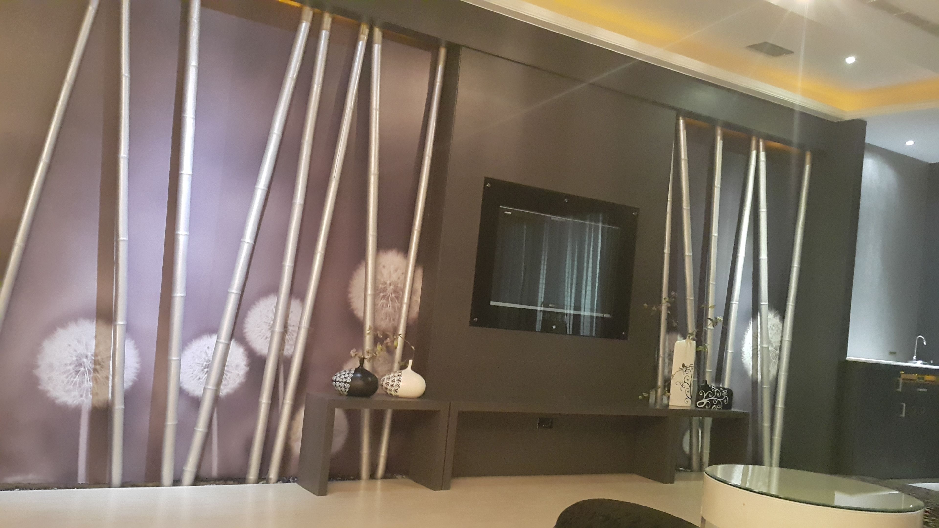 Ein modernes Badezimmer mit einer Duschkabine aus Glas, einer dunklen Wand mit Fenster und einem Spiegel, der den Duschbereich reflektiert.
