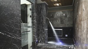 A modern bathroom with a marble sink, a shower with a glass enclosure, and a tiled wall. - Dryad Motel (Tainan)