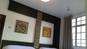 A hotel room with two beds, a large window with curtains, and two wall-mounted floral artwork. - Cameron Highlands Premier Apartment at Crown Imperial Court (Brinchang)