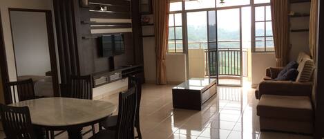 A modern living room with a dining area, a sofa, a TV, and a balcony with curtains.