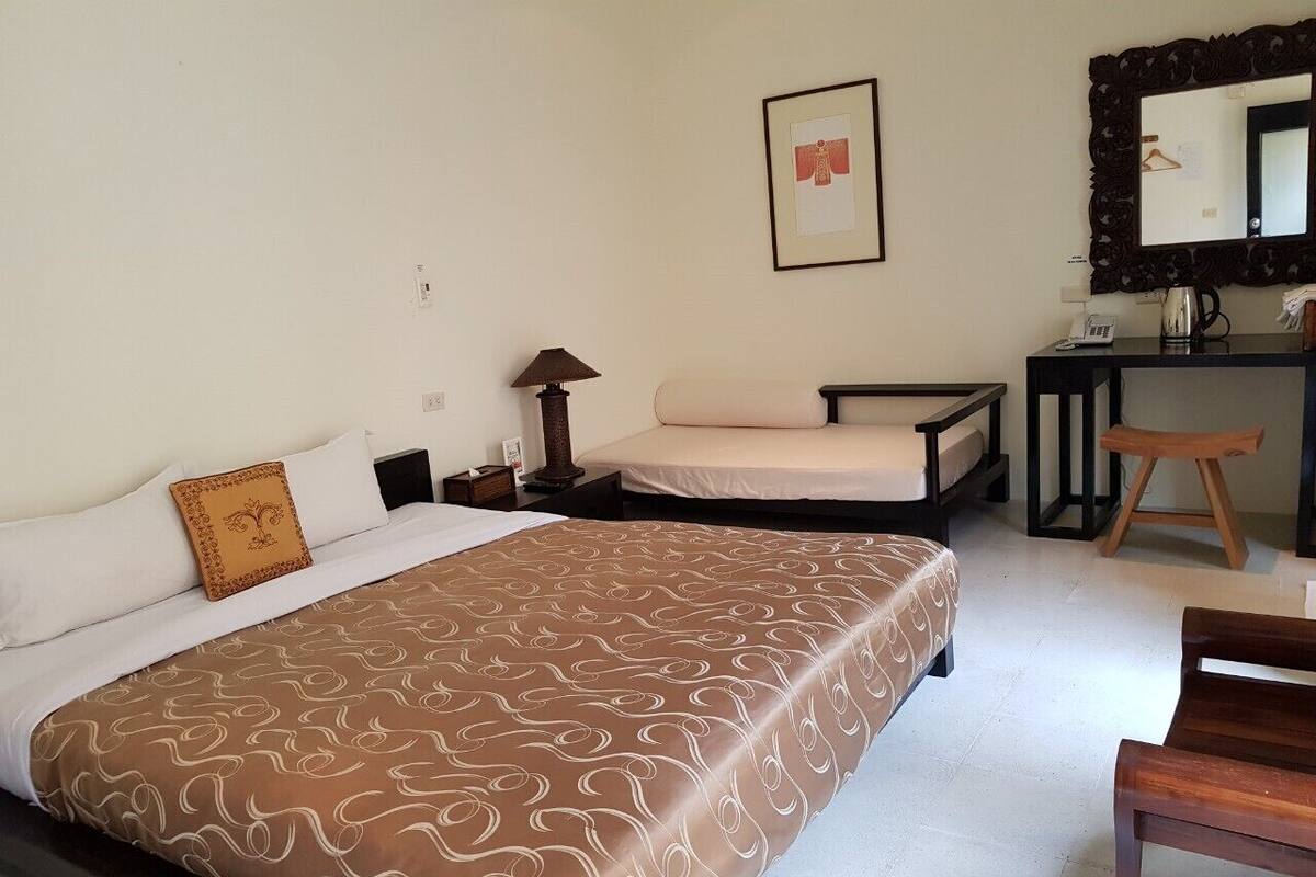 Habitación de hotel con cama, mesitas de noche, escritorio, silla, lámpara, espejo y un cuadro en la pared.