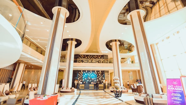 A spacious lobby with high ceilings, large columns, and a central reception desk. - Muong Thanh Luxury Ca Mau Hotel (Tan Thanh)