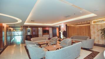 A modern lobby with a reception desk, seating area, and a sign for 'TRAM Spa & Wellness'.