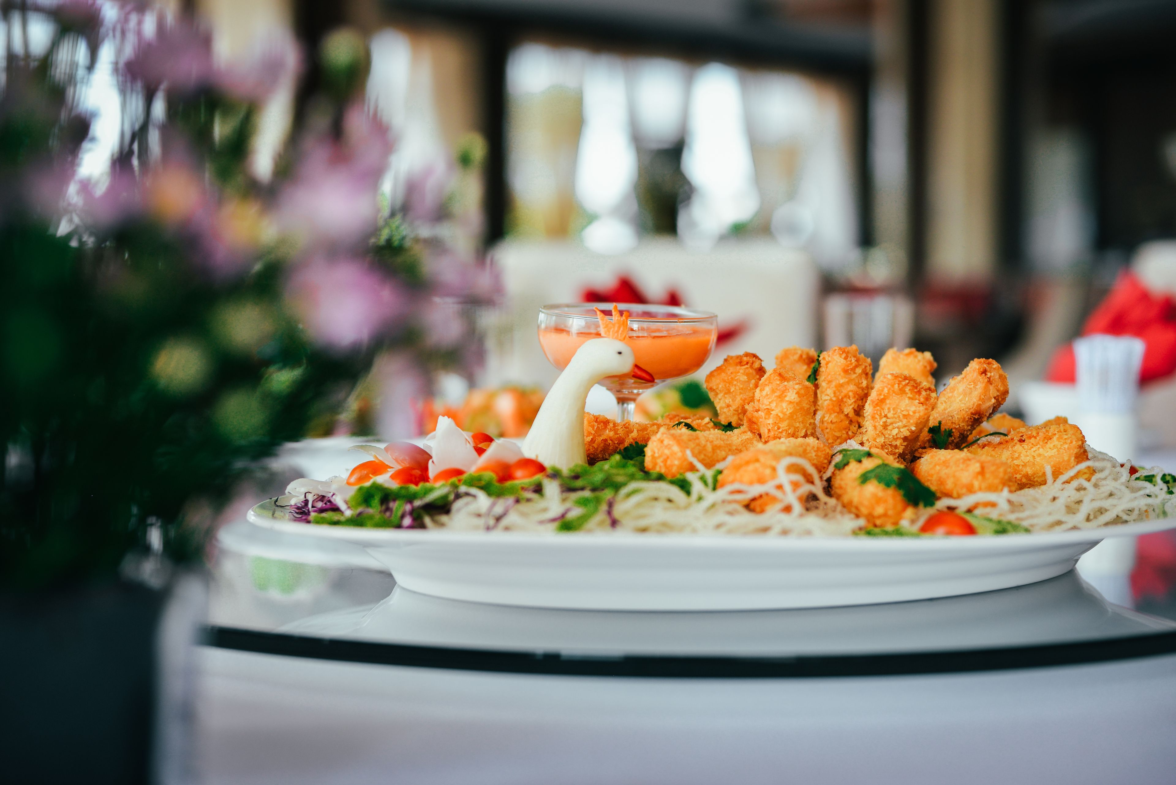 Un plato de comida con una decoración de fideos y vegetales, adornado con una forma de cisne.