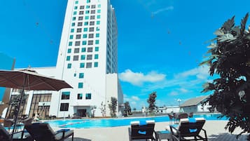 Una piscina al aire libre, sillones reclinables de piscina