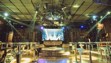 A stage with a large screen displaying text, surrounded by metallic structures and seating.