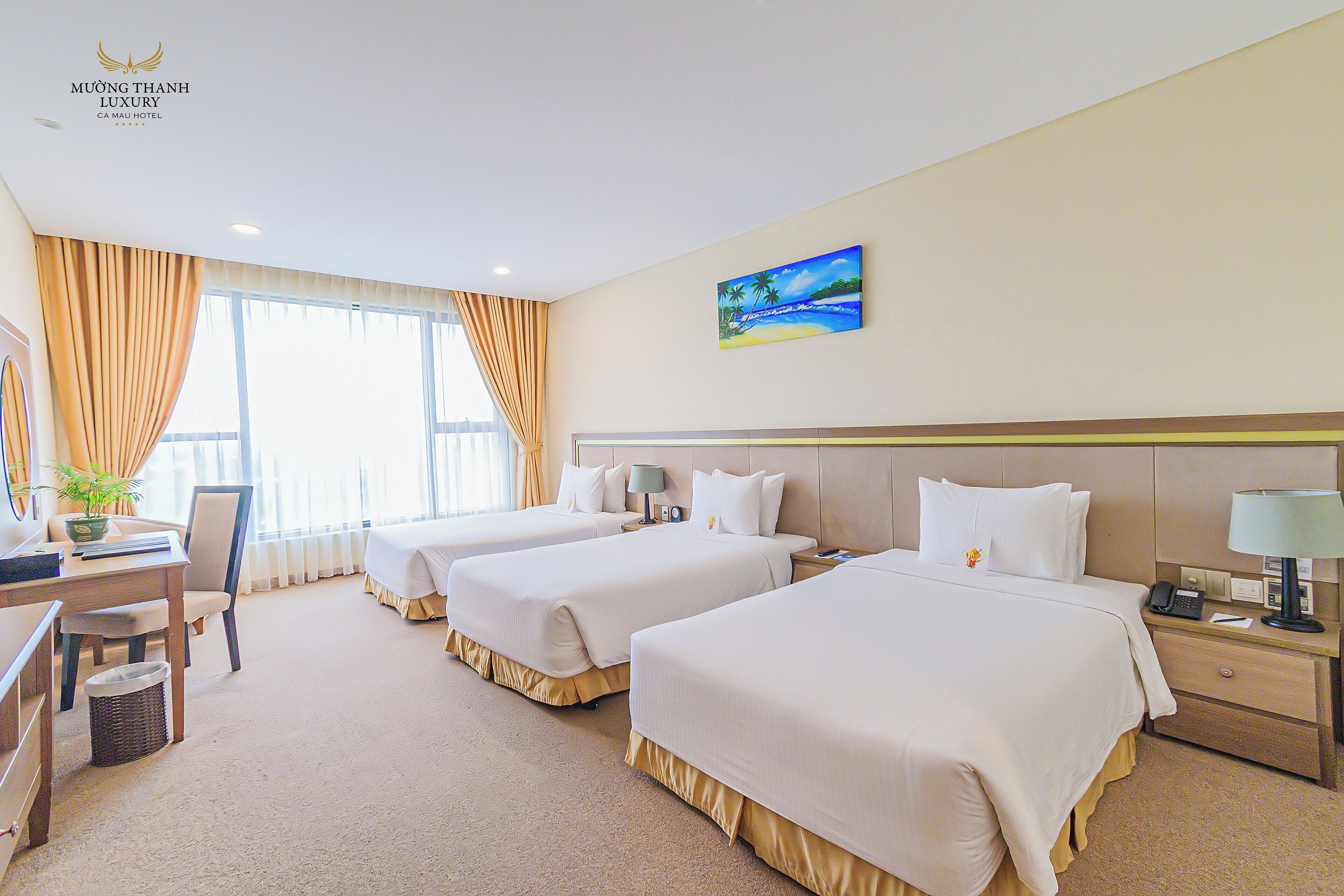 A hotel room with two beds, a desk, a chair, a lamp, and a painting on the wall.