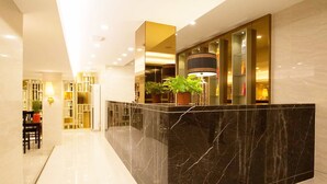 A modern reception area with a marble counter, potted plants, and a well-lit interior. - Shwe Pyi San Yar Hotel (Yangon)