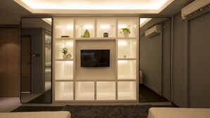 Una habitación de hotel moderna con un televisor de pantalla plana grande, montado en una pared con estantes integrados.