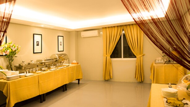 A room with a buffet setup, a window with curtains, and framed pictures on the wall. - Shwe Pyi San Yar Hotel (Yangon)