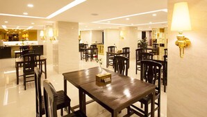 Un comedor moderno con una mesa central, rodeada de sillas, y una cocina al fondo.