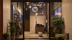 A reception area with a wooden desk, potted plants, and a large spherical light fixture. - Tourism Inn (Tainan)