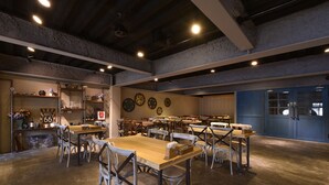 A spacious dining area with multiple tables and chairs, a bar area with shelves and decorative items, and a wall with clocks. - Tourism Inn (Tainan)