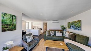 Una sala de estar moderna con un sofá, un sillón, una mesa de centro y cuadros en las paredes.
