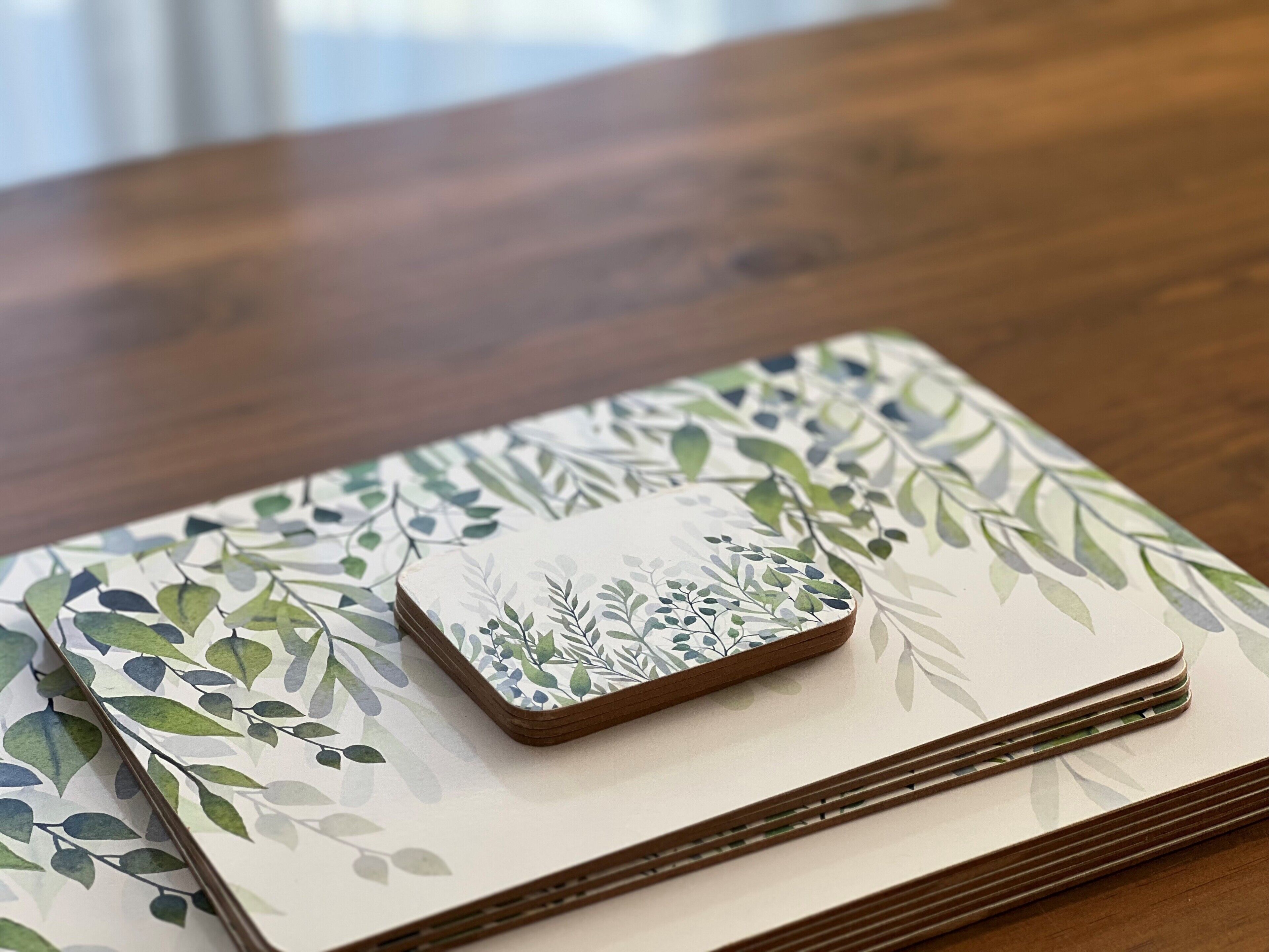 Una pila de cuadernos con un diseño de hojas sobre una superficie de madera.